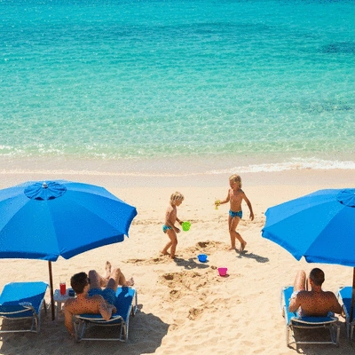 Family enjoying a beach vacation, with children playing in the sand and adults relaxing under umbrellas